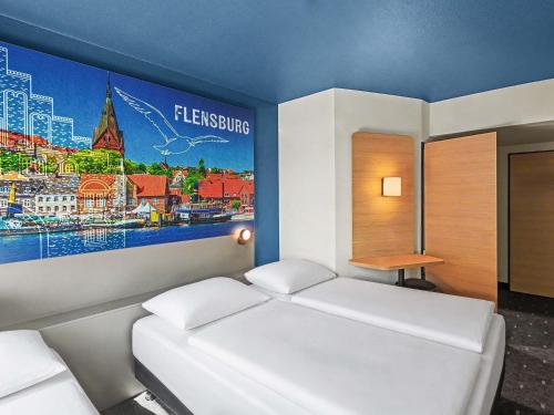 a bedroom with two beds and a painting on the wall at B&B HOTEL Flensburg-City in Flensburg