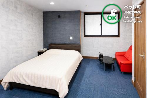 a bedroom with a bed and a red couch at ホテルサルビア in Tendo