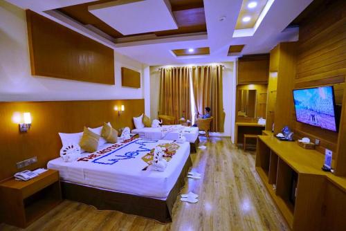 a hotel room with a large bed and a flat screen tv at The Hotel Nova in Mandalay