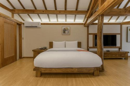 a bedroom with a large white bed and a television at The Seaes Hotel & Resort in Seogwipo