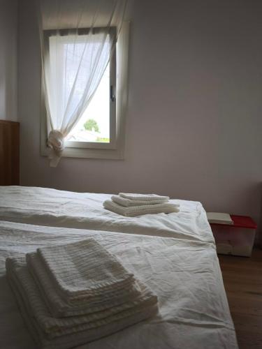 a bedroom with a bed with white sheets and a window at L'Albero del Tempo in Falze