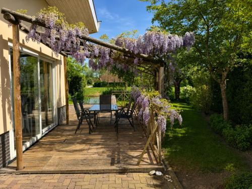 a pergola covered in wisteria on a patio at Villa Vera - Comfort, Space, Sauna & Hot Tub in Private Garden in Zeewolde