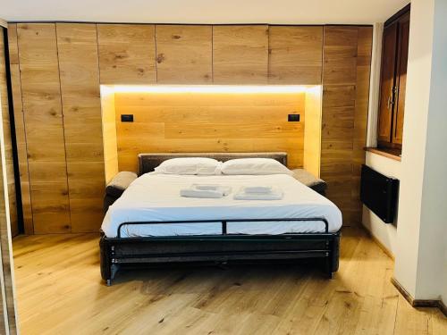 a bedroom with a bed with a wooden wall at GuestHost - Mulino del Bianco - Comfy Studio-Flat in La Thuile