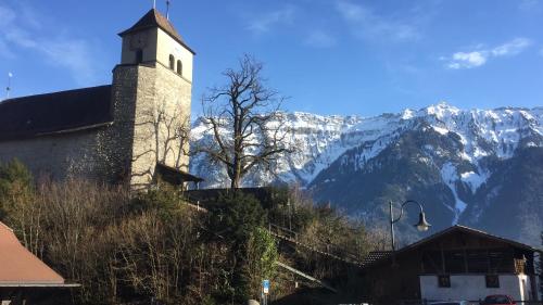 a building with a clock tower in front of a mountain at Royal Swiss Apartments in Ringgenberg