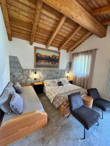 a bedroom with a bed and a couch and chairs at B&B Casa il sasso in Pinzolo