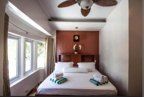 a bedroom with a large bed with a ceiling fan at Green Monkey Resort Boracay in Boracay