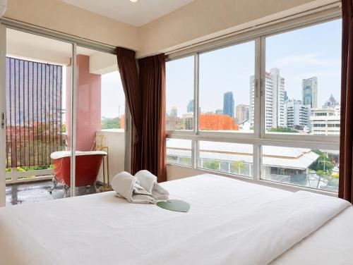 a bedroom with a bed and a large window at Baan Sabai Rama IV Apartment in Bangkok