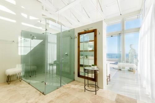 a bathroom with a glass shower and a table at White Water Retreat - Pinnacle Point in Mossel Bay