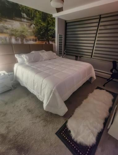 a bedroom with a large white bed and a window at The River Condos in Detroit