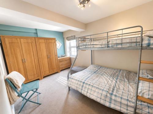 a bedroom with two bunk beds and a chair at Dog friendly sea front apartment with balcony in Pendine