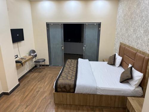 a bedroom with a bed and a desk and a television at Hotel Keshav Villa in Mandhana