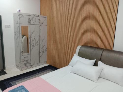 a bedroom with a bed and a wooden wall at Kenari homestay in Gopeng
