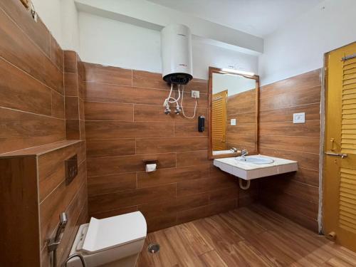 a bathroom with a toilet and a sink and a mirror at Hotel Naina Rockland , Manali in Vashisht