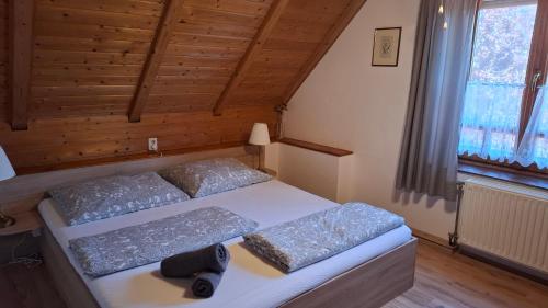 a bedroom with a bed with two pillows and a window at Diófa Vendégházak in Tiszafüred