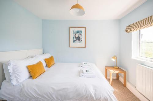 a bedroom with a white bed with yellow pillows and a window at Drift Cottage, Rendlesham in Rendlesham