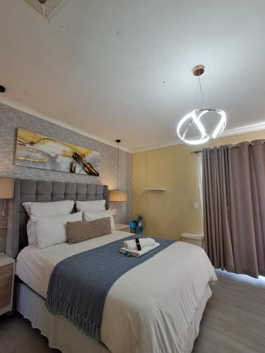 a bedroom with a large white bed and a chandelier at Naliya Guest house in Cape Town