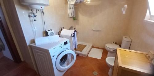 a bathroom with a washing machine and a toilet at Casa Dominique in São Pedro do Corval