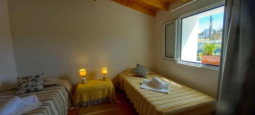 two beds in a room with a window at Casa Dominique in São Pedro do Corval