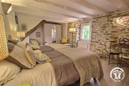 a bedroom with two beds and a stone wall at Au charme de la forêt in Belle-Isle-en-Terre