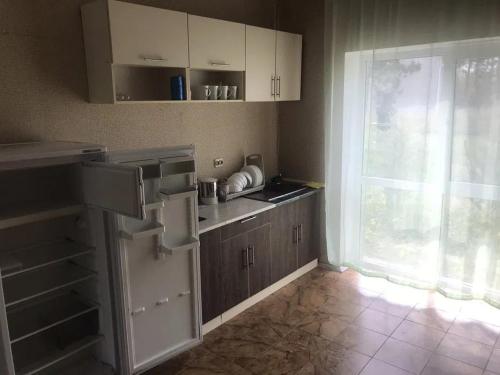a kitchen with white cabinets and a large window at Море і Сосни in Koblevo
