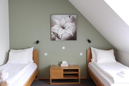 two beds with white sheets and a table in a room at Neeme Marina Questhouse in Neeme