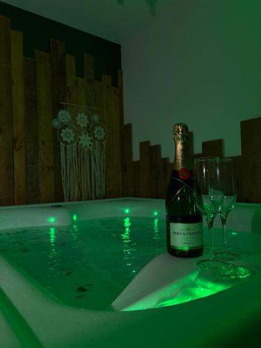 a bottle of champagne and a wine glass on a bath tub at Hédoné LoveRooms in La Chapelle