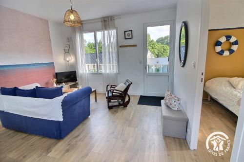 a living room with a blue couch and a bedroom at Le sémaphore in Saint-Cast-le-Guildo
