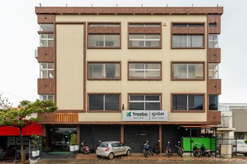 a building with a car parked in front of it at Treebo Jaguar Comforts, 3 Kms From Mahatma Gandhi Park in Chikmagalūr