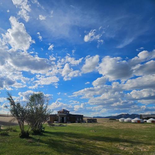 a field with a blue sky with clouds at Mongol Altai Tour Camp in Högönö-Taranaiin-Hüree