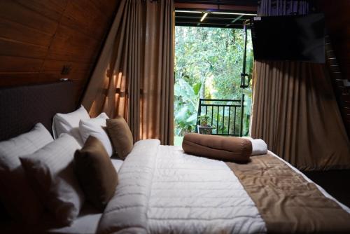 a bedroom with a large bed with a large window at Ro Cabin in Ella