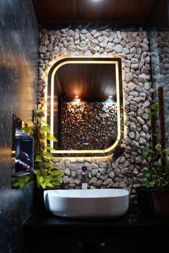 a bathroom with a stone wall with a sink and a mirror at Ro Cabin in Ella