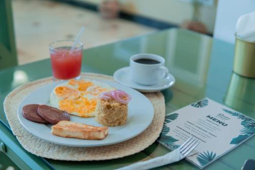 Ein Teller mit Frühstücksspeisen und ein Getränk auf einem Tisch in der Unterkunft Hotel Checkin El Cortecito in Punta Cana
