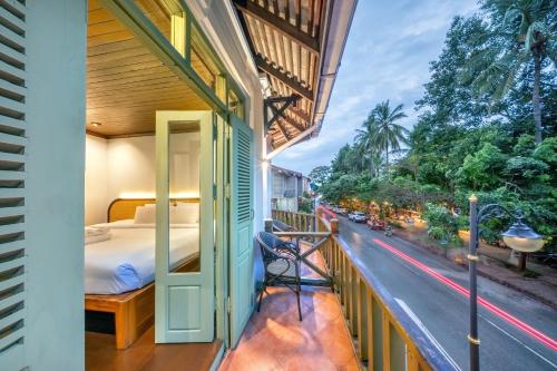 a balcony with a bed and a view of a street at Nava Luang Prabang Hotel in Luang Prabang