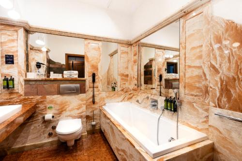 a bathroom with a tub and a toilet and a sink at Hotel Rubinstein in Krakow