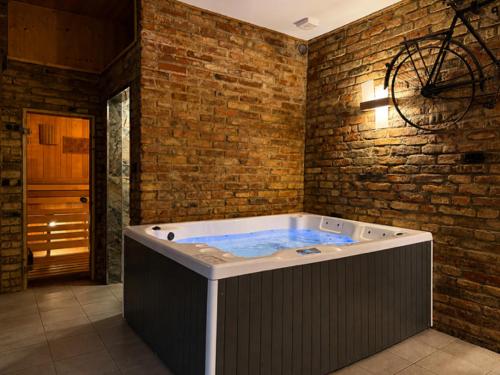 a hot tub in a room with a brick wall at Domek pod Warszawą z sauną in Raszyn