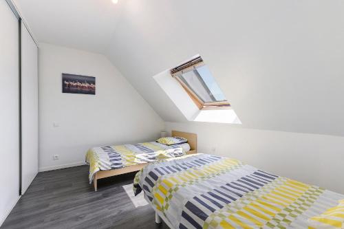 two beds in a attic bedroom with a window at Maison La Plouhinecoise in Plouhinec