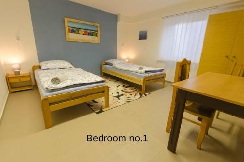 a room with two beds and a table and a desk at Prízemný apartmán Anika s veľkým parkovaním in Nitra