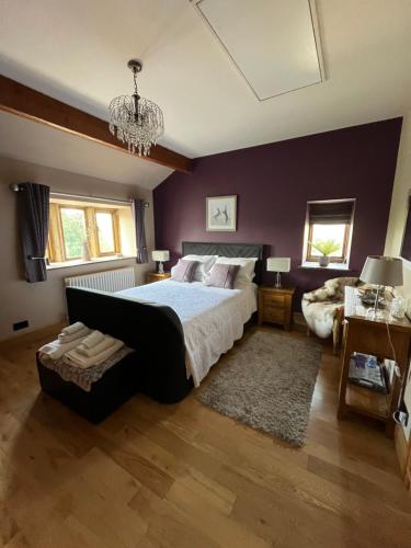 a bedroom with a large bed and a chandelier at Weather Hill Cottage, Hebden Bridge in Hebden Bridge