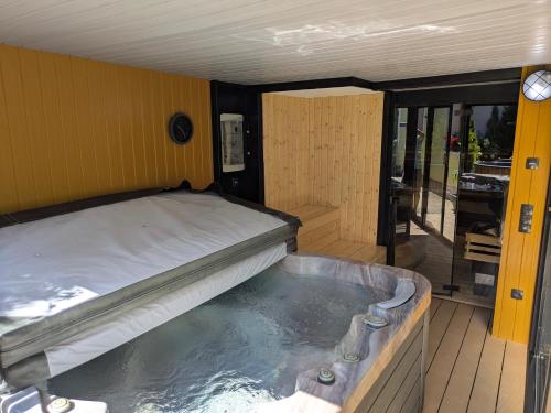 a bed in a room with a hot tub at Škorničkův statek - Tátova chalupa s wellness za příplatek in Hamr
