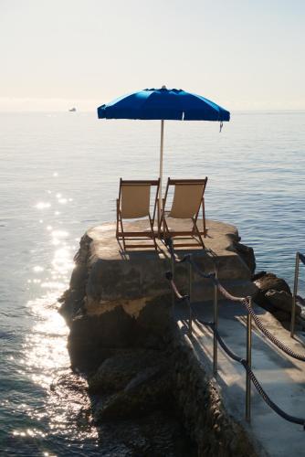 two chairs and an umbrella on the edge of the water at Hotel Carasco in Lipari