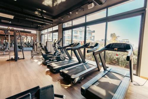 a gym with several treadmills in a room with windows at Luxury Sea & Pool View Apt at Caesar Cliff Esentepe in Perivolia tou Trikomou