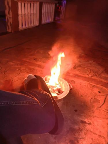 a person sitting next to a fire in the street at Amazon half london in Boma la Ngombe