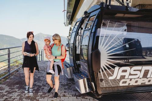 Zwei Frauen und ein Kind stehen neben einem Zug. in der Unterkunft Hotel Ostredok in Demänovská Dolina