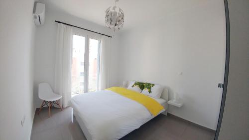 a white bedroom with a bed and a window at KYMA Apartments - Athens Acropolis 6 in Athens