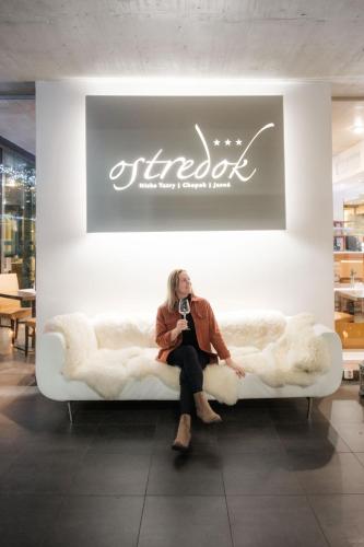 Eine Frau sitzt auf einem Sofa in einem Geschäft in der Unterkunft Hotel Ostredok in Demänovská Dolina