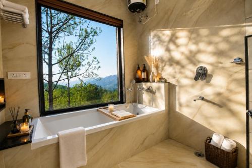 a bathroom with a tub and a large window at Minara Meadows Kasauli in Dharampur