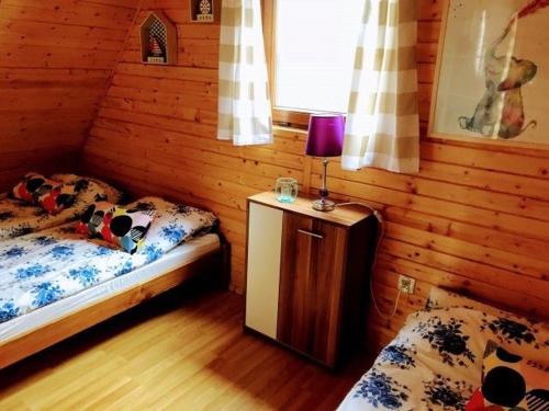 a bedroom with two beds and a table with a lamp at Domki Relaksowa in Nowęcin