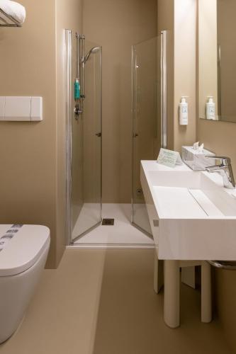 a bathroom with a shower and two sinks and a toilet at Hotel Bristol in Sottomarina