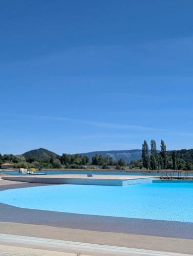 a large blue swimming pool with trees in the background at les Trois Cœurs in Mison