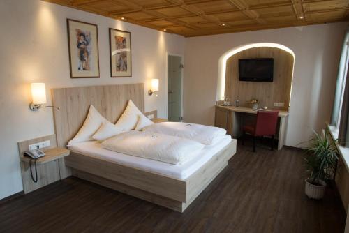 a bedroom with a bed and a desk and a television at Hotel Deutsches Haus in Dinkelsbühl